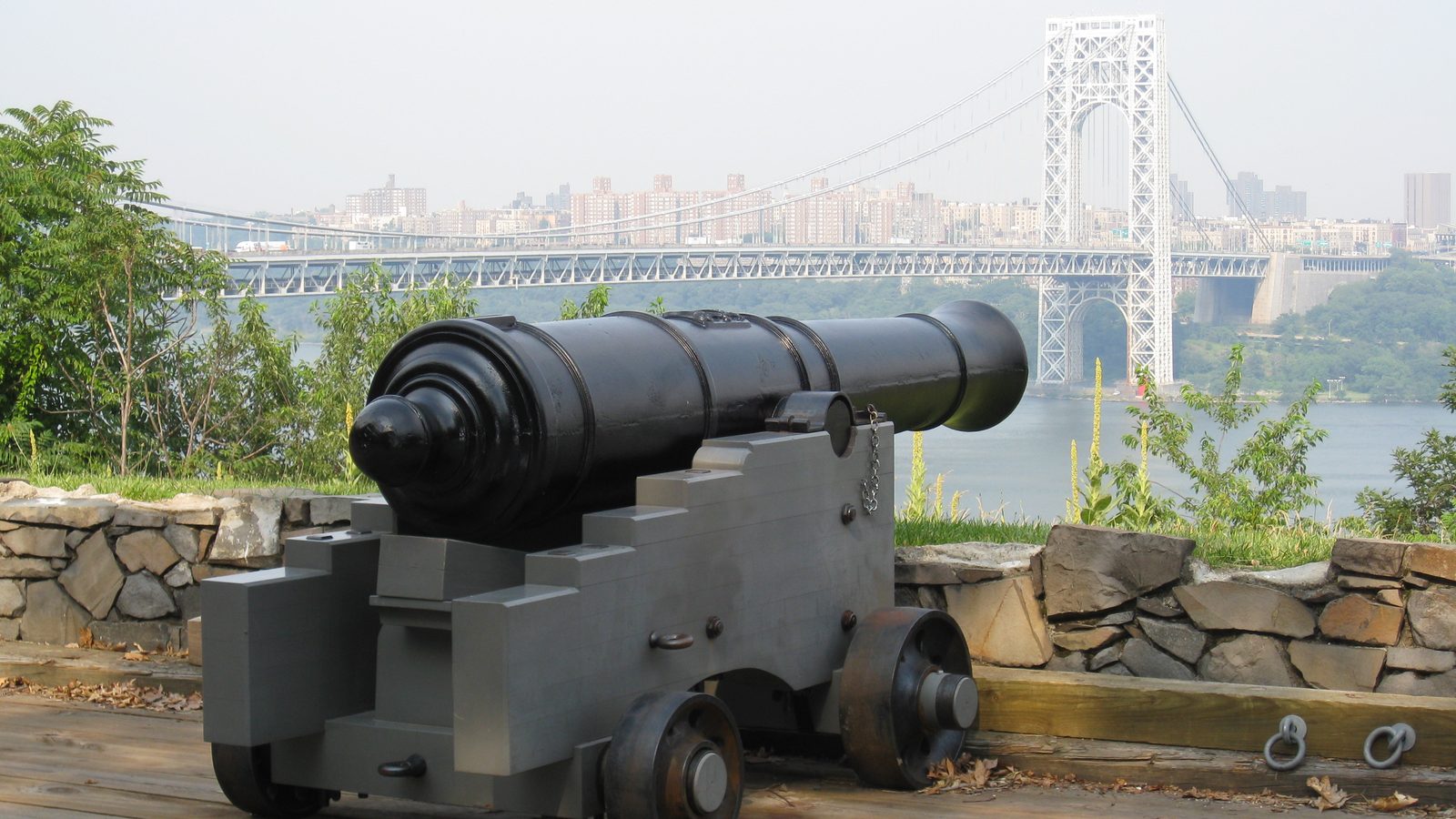 A historic cannon at Fort Lee Historic Park with the George Washington Bridge and Manhattan behind, in Fort Lee, NJ
