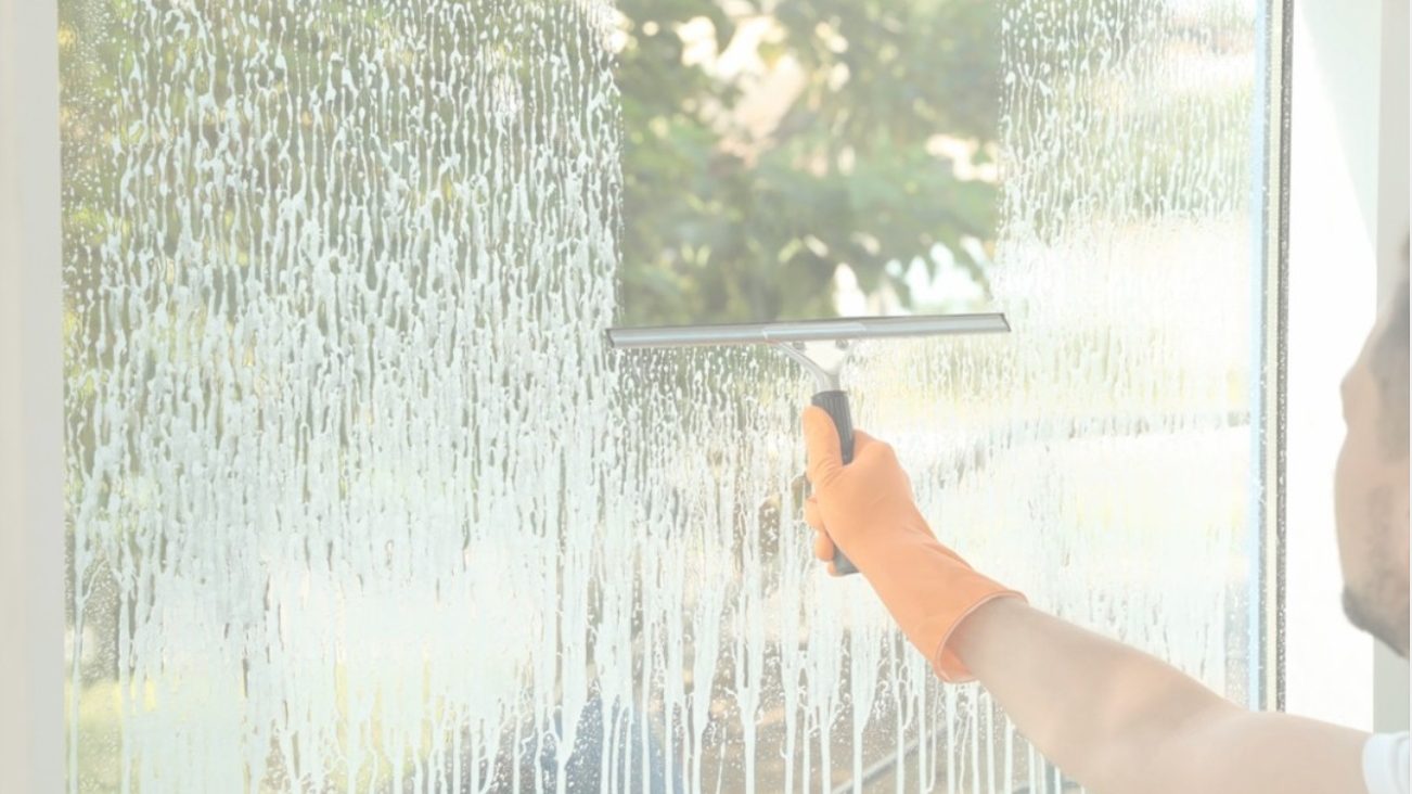 Squeegee pulling a clean streak-free stripe down a large soapy plate-glass storefront window during a commercial window cleaning in Bergen County, NJ